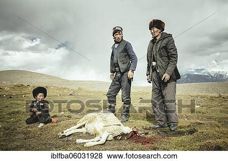 Two men and a boy after slaughtering a sheep, the sheep lies with its neck cut on a mountain meadow, Kyrgyz nomads, Khadz Goz, Wakhan Corridor, Badakhshan, Afghanistan, Asia View Large Photo Image Stock Photo - Two men and a boy after slaughtering a sheep, the sheep lies with its neck cut on a mountain meadow, Kyrgyz nomads, Khadz Goz, Wakhan Corridor, Badakhshan, Afghanistan, Asia. Fotosearch