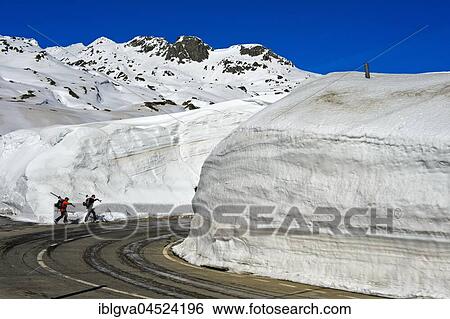 Two skiers in front of high snow walls, pass road to the Gotthard Pass, Canton Ticino, Switzerland, Europe View Large Photo Image Stock Photograph - Two skiers in front of high snow walls, pass road to the Gotthard Pass, Canton Ticino, Switzerland, Europe. Fotosearch