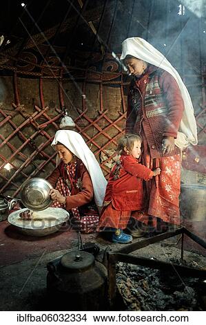 Picture - Two woman and a child in traditional Kyrgyz traditional traditional traditional traditional traditional traditional traditional traditional traditional costume, dough making for flat bread, in front of her a teakettle on a fireplace, yurt, bozai.... Fotosearch