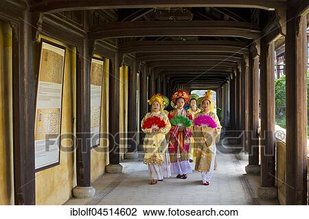 Stock Image - Vietnamese extras in traditional robes walking through imperial palace Hoang Thanh, Forbidden City, Hue, Vietnam, Asia. Fotosearch