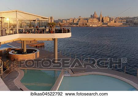 Stock Image - View from Sliema of Valletta, in front Restaurant The Terrace and Pool, Evening Light, Valletta, Malta, Europe. Fotosearch