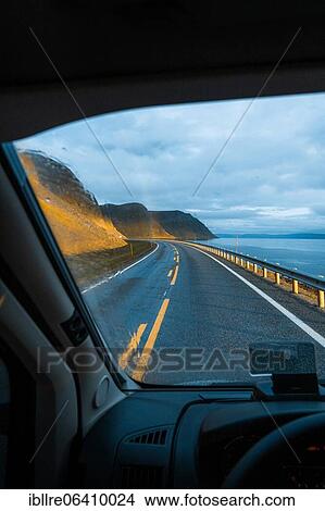 Picture - View on road leading to rainbow with dramatic sky and sunset light, Sarnes, North Cape, Norway, Europe. Fotosearch