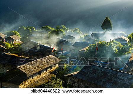 Stock Image - View on village in morning light, smoke is coming out of the houses, Ghandruk, Kaski District, Nepal, Asia. Fotosearch