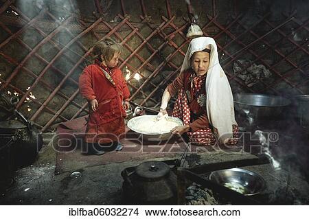 Picture - Woman and infant in traditional Kyrgyz traditional traditional traditional traditional traditional traditional traditional traditional traditional costume, dough production for flat bread, in front of her a teakettle on a fireplace, yurt, bozai.... Fotosearch