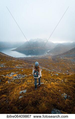 Woman looking at the village Fjordbotn and a prominent and pointed mountain, snowfall in autumnal fjord landscape, Fjordgard, Senja, Norway, Europe View Large Photo Image Stock Photo - Woman looking at the village Fjordbotn and a prominent and pointed mountain, snowfall in autumnal fjord landscape, Fjordgard, Senja, Norway, Europe. Fotosearch
