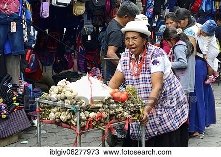 Stock Image - Woman pushing a trolley with garlic at the market, Otavalo, Imbabura province, Ecuador, South America. Fotosearch