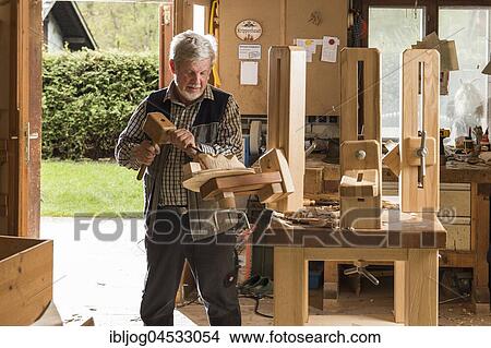 Picture - Wooden mask carver using wood carving tools at workbench in workshop, Bad Aussee, Styria, Austria, Europe. Fotosearch