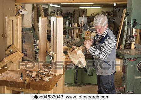 Stock Image - Wooden mask carver using wood carving tools on a wooden block, wooden mask carver, workbench, Bad Aussee, Styria, Austria, Europe. Fotosearch