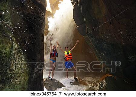Stock Photo - Young couple under waterfall at the canyon of Wadi Mujib, Jordan, Asia. Fotosearch