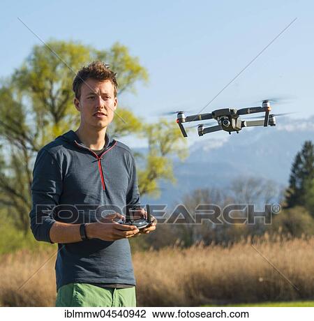 Young man controlling flying quadrocopter, remote controlled drone with camera, DJI Mavic View Large Photo Image Stock Image - Young man controlling flying quadrocopter, remote controlled drone with camera, DJI Mavic. Fotosearch