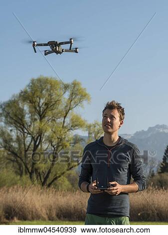 Young man controlling flying quadrocopter, remote controlled drone with camera, DJI Mavic View Large Photo Image Stock Photo - Young man controlling flying quadrocopter, remote controlled drone with camera, DJI Mavic. Fotosearch