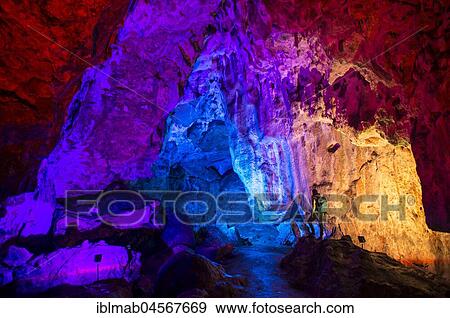 Stock Photo - Young man looks at colorfully illuminated stalactite cave, Nebelhöhle, Sonnenbühl, Swabian Alb, Baden-Württemberg, Germany, Europe. Fotosearch