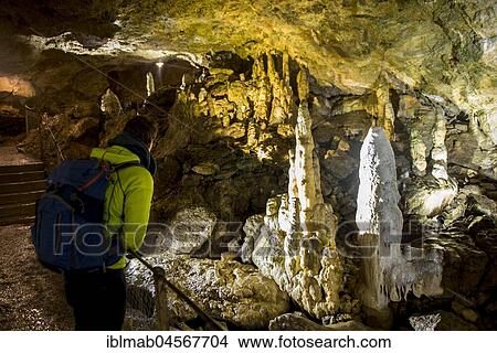 Picture - Young man looks at illuminated stalactites and stalacmites, Nebelhöhle, Sonnenbühl, Swabian Alb, Baden-Württemberg, Germany, Europe. Fotosearch