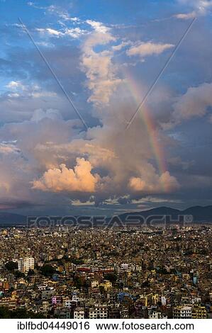 Stock Photograph - Aerial view from Swayambhunath Temple, houses in city, thunderstorm clouds, rainbow, Kathmandu, Kathmandu District, Nepal, Asia. Fotosearch