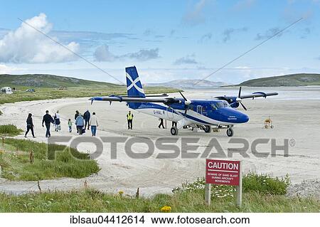 Airport and aircraft Twin Otter from Scottish airline Loganair, passengers when boarding, Airfield on sandy beach, Barra Airport, BRR, Isle of Barra, Outer Hebrides, Scotland, United Kingdom, Europe View Large Photo Image Picture - Airport and aircraft Twin Otter from Scottish airline Loganair, passengers when boarding, Airfield on sandy beach, Barra Airport, BRR, Isle of Barra, Outer Hebrides, Scotland, United Kingdom, Europe. Fotosearch