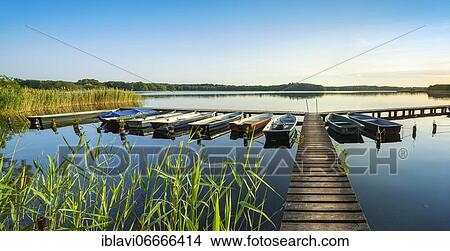 Picture - At the Schaalsee, wooden jetty with boats and reeds in the evening light, Schaalsee Biosphere Reserve, Mecklenburg-Western Pomerania, Germany, Europe. Fotosearch