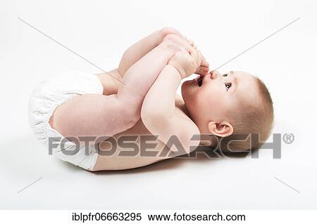 Stock Photography - Baby lies on back and plays with his feet. Fotosearch
