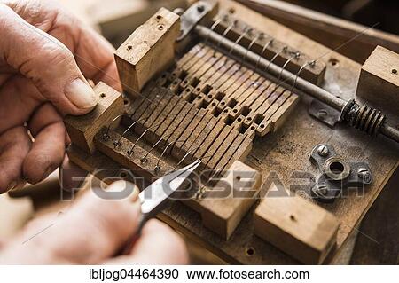 Stock Image - Barrel organ builder, hand bends spring wires made of V2A steel into wooden valves, Grassau, Upper Bavaria, Bavaria, Germany, Europe. Fotosearch