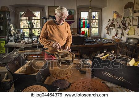 Barrel organ builder, workshop, man checks spring wires of sound post on body, empty case on the left, perforated disks in front, open Amorette on the right, Grassau, Upper Bavaria, Bavaria, Germany, Europe View Large Photo Image Stock Photo - Barrel organ builder, workshop, man checks spring wires of sound post on body, empty case on the left, perforated disks in front, open Amorette on the right, Grassau, Upper Bavaria, Bavaria, Germany, Europe. Fotosearch