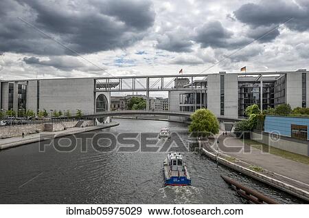 Stock Photo - Boat on the Spree, Marie-Elisabeth-Lüders-House and Paul-Löbe-House near cloudy sky, government district, Mitte, Berlin, Germany, Europe. Fotosearch