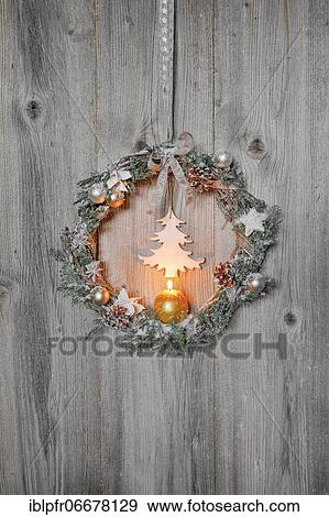 Stock Photo - Christmas wreath on wooden wall with candle. Fotosearch