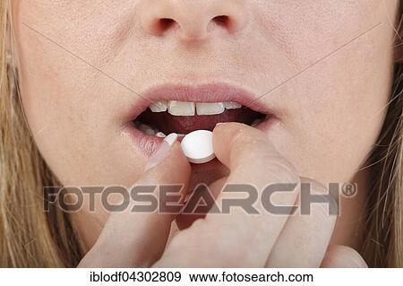Close-up of young woman taking a pill View Large Photo Image Stock Photo - Close-up of young woman taking a pill. Fotosearch