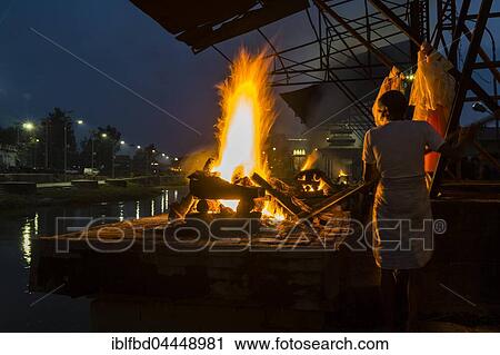 Stock Image - Cremation of a dead body at the burning ghats at night, Pashupatinath temple, banks of Bagmati River, Kathmandu, Kathmandu District, Nepal, Asia. Fotosearch
