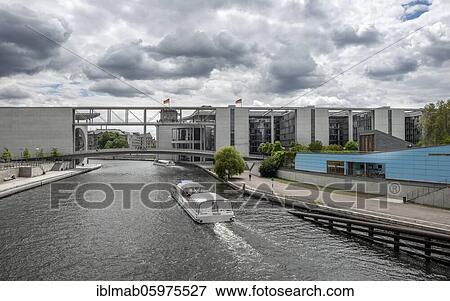 Stock Photo - Excursion boat on the Spree, Marie-Elisabeth-Lüders-House and Paul-Löbe-House near cloudy sky, government district, Mitte, Berlin, Germany, Europe. Fotosearch