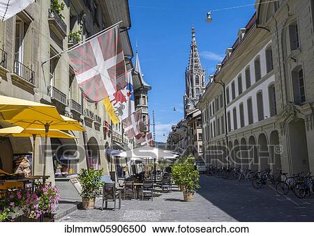 Stock Image - Flags on a row of houses in the old town of Bern, behind tower of the Bern Cathedral, Inner City, Bern, Canton Bern, Switzerland, Europe. Fotosearch