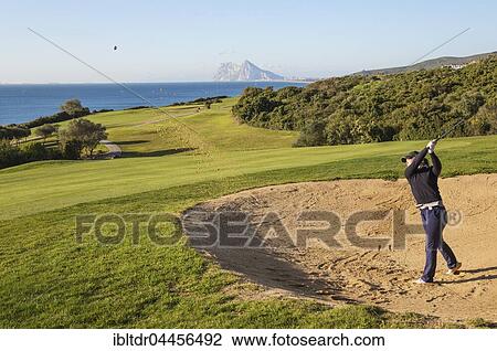 Golfer hitting from bunker at La Alcaidesa Golf Resort with Mediterranean Sea and Rock of Gibraltar, Cádiz, Andalusia, Spain, Europe View Large Photo Image Stock Image - Golfer hitting from bunker at La Alcaidesa Golf Resort with Mediterranean Sea and Rock of Gibraltar, Cádiz, Andalusia, Spain, Europe. Fotosearch
