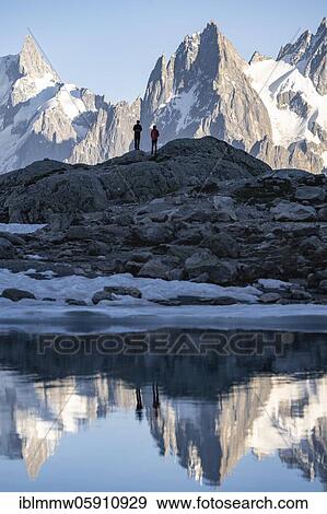Stock Photo - Hikers in front of a mountain panorama with water reflecting in Lac Blanc, mountain peaks, Grandes Jorasses and the Mont Blanc massif, Chamonix-Mont-Blanc, Haute-Savoie, France, Europe. Fotosearch