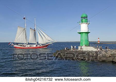 Stock Image - Lighthouse with sailing boat at back, Hanse Sail, harbour entrance Warnemünde, port entrance, Mecklenburg-Western Pomerania, Germany, Europe. Fotosearch