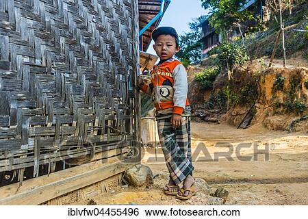 Stock Photograph - Little boy stands in front of log cabin, Palaung hilltribe, Palaung Village in Kyaukme, Shan State, Myanmar, Asia. Fotosearch