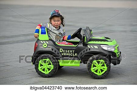Stock Image - Little girl rides in electric toy car, Genghis Khan Square, Ulaanbaatar, Mongolia, Asia. Fotosearch
