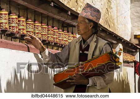 Local man, carrying a prayer book, is walking along the wall with spinning prayer wheels, Marpha, Mustang District, Nepal, Asia View Large Photo Image Stock Photography - Local man, carrying a prayer book, is walking along the wall with spinning prayer wheels, Marpha, Mustang District, Nepal, Asia. Fotosearch