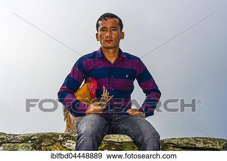 Stock Photo - Local man sitting with a rooster, soon to be sacrificed at the Khadga Devi Mandir Temple, Darsain Hindu Festival, Bandipur, Tanahun, Nepall. Fotosearch