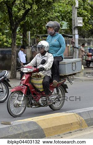 Man on moped and woman sitting on a box, Phnom Penh, Cambodia, Asia View Large Photo Image Stock Image - Man on moped and woman sitting on a box, Phnom Penh, Cambodia, Asia. Fotosearch