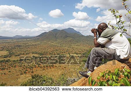 Man with binoculars looking at the Ngulia Hills and the Rhino Valley, Tsavo West National Park, Taita-Taveta County, Kenya, Africa View Large Photo Image Stock Image - Man with binoculars looking at the Ngulia Hills and the Rhino Valley, Tsavo West National Park, Taita-Taveta County, Kenya, Africa. Fotosearch