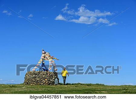 Stock Image - Mongolian man performing prayer ritual beside ovoo, sacred stone heap, Arkhangai, Mongolia, Asia. Fotosearch