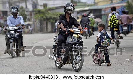 Stock Image - Mopeds and child with bike on the road, Phnom Penh, Cambodia, Asia. Fotosearch