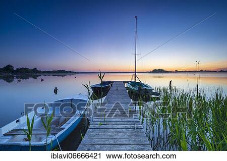 Morning glow at Schaalsee, wooden jetty with boats and reeds, Schaalsee Biosphere Reserve, Mecklenburg-Western Pomerania, Germany, Europe View Large Photo Image Stock Image - Morning glow at Schaalsee, wooden jetty with boats and reeds, Schaalsee Biosphere Reserve, Mecklenburg-Western Pomerania, Germany, Europe. Fotosearch