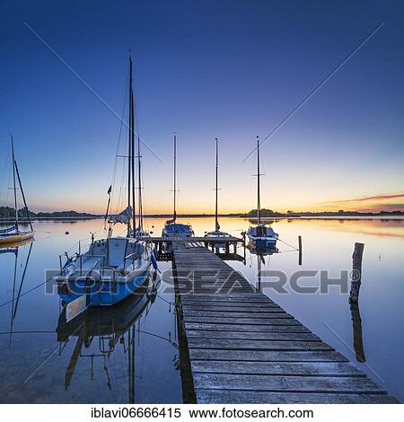 Morning glow at Schaalsee, wooden jetty with sailing boats, Schaalsee Biosphere Reserve, Mecklenburg-Western Pomerania, Germany, Europe View Large Photo Image Stock Photography - Morning glow at Schaalsee, wooden jetty with sailing boats, Schaalsee Biosphere Reserve, Mecklenburg-Western Pomerania, Germany, Europe. Fotosearch