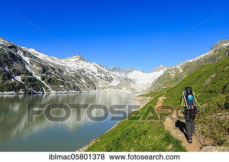 Stock Photo - Mountaineer at the Oberaarsee in the direction of Oberaar Glacier, Canton Bern, Switzerland, Europe. Fotosearch