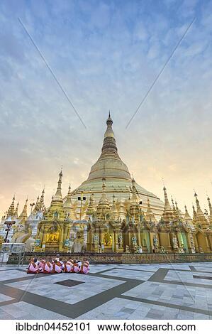 Stock Image - Nuns sitting in front of the Shwedagon pagoda, Shwedagon Paya, morning light, Yangon, Myanmar, Asia. Fotosearch