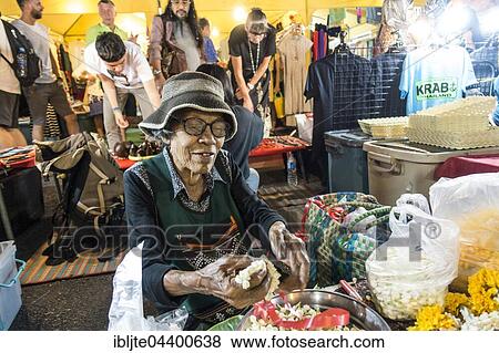 Stock Photo - Old woman, Thai woman sells flowers and flower chains at the Night Market, Krabi Town, Krabi Province, Thailand, Asia. Fotosearch