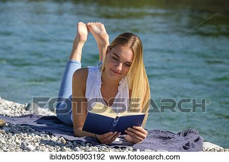 Portrait young blonde woman reading a book at the water, summer, river Isar, Lenggries, Upper Bavaria, Bavaria, Germany, Europe View Large Photo Image Stock Image - Portrait young blonde woman reading a book at the water, summer, river Isar, Lenggries, Upper Bavaria, Bavaria, Germany, Europe. Fotosearch