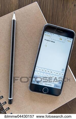 Stock Photo - Product ideas typed on smartphone screen, notebook and pen on a wooden table. Fotosearch