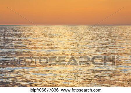 Stock Photograph - Reflecting colors of the sunset at the sea, Scotland, Great Britain. Fotosearch