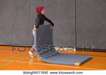 Stock Image - Schoolgirl wearing floor mat, Physical Education, Primary School, Lower Saxony, Germany, Europe. Fotosearch