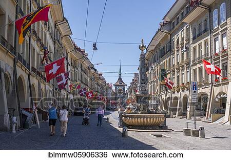 Stock Photograph - Simson fountain, flags on a row of houses in the old town of Bern, clock tower Zytglogge in the back, Innere Stadt, Bern, Canton Bern, Switzerland, Europe. Fotosearch